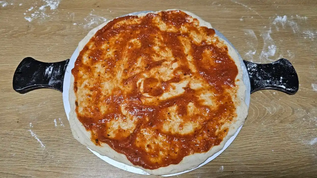 Na pizza těsto těsto nejprve rozetřeme sugo.